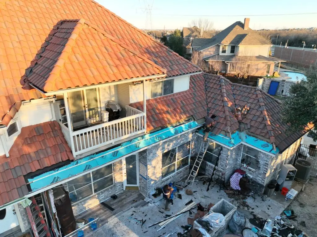 Exposed roof sheathing and underlayment during tile roof edge repair in Texas